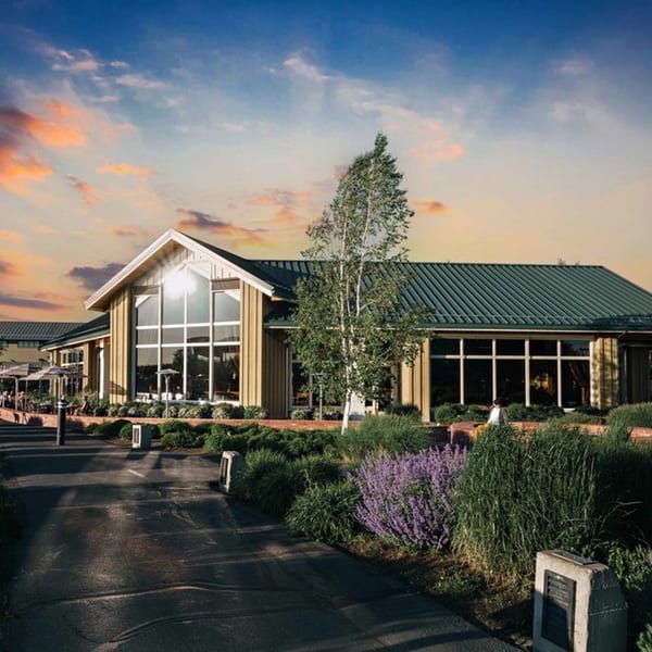 Exterior of Greg's Grill steakhouse at sunset, with large windows and outdoor patio seating.