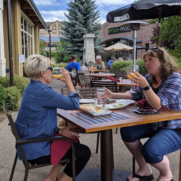Two women enjoying drinks and appetizers on the Greg's Grill outdoor patio.